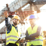 A pair of contractors discussing a job while working on a construction site.